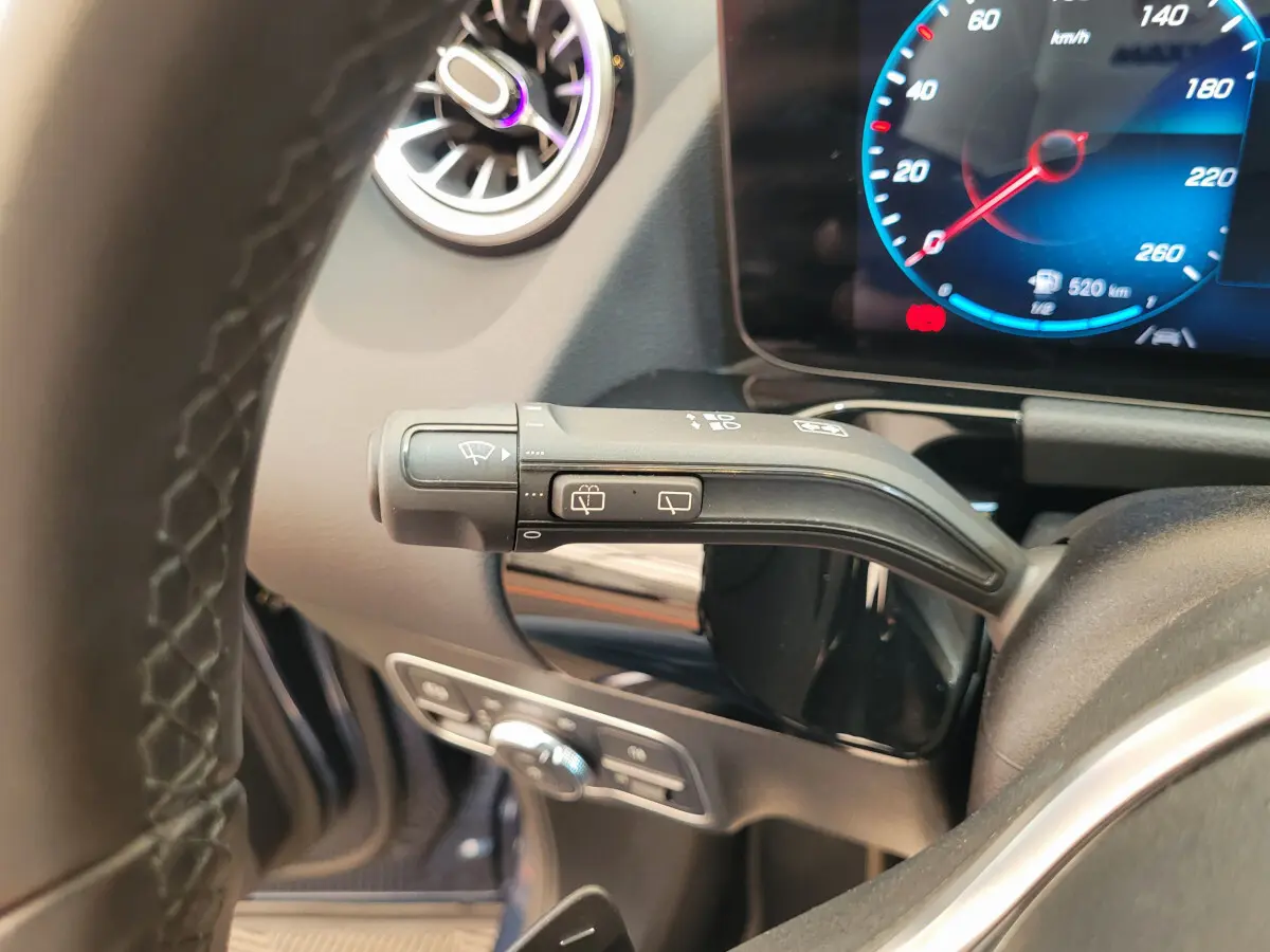Gros plan sur la manette d'essuie-glace à gauche du volant cuir du Mercedes GLA 200 D bleu 2022, tableau de bord numérique visible.