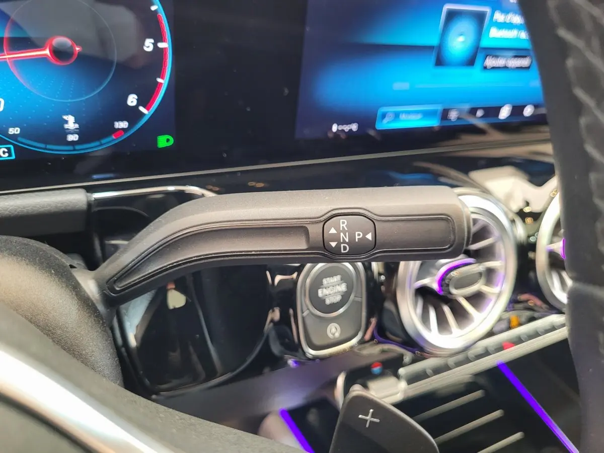 Gros plan intérieur sur la commande de boîte automatique et le tableau de bord numérique du Mercedes GLA 200 D bleu.