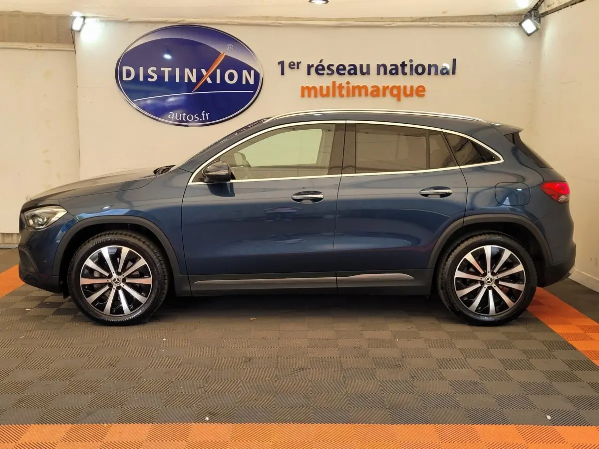 Profil latéral droit d'un Mercedes GLA 200 D Business Line bleu, avec jantes alliage et vitres teintées en showroom.