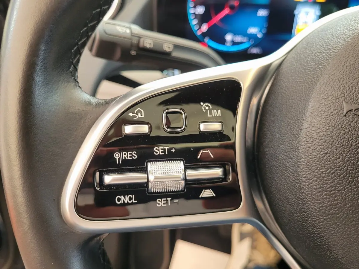 Gros plan sur les commandes du volant cuir noir du Mercedes GLA 200 D Business Line 2022, avec affichage digital en arrière-plan.