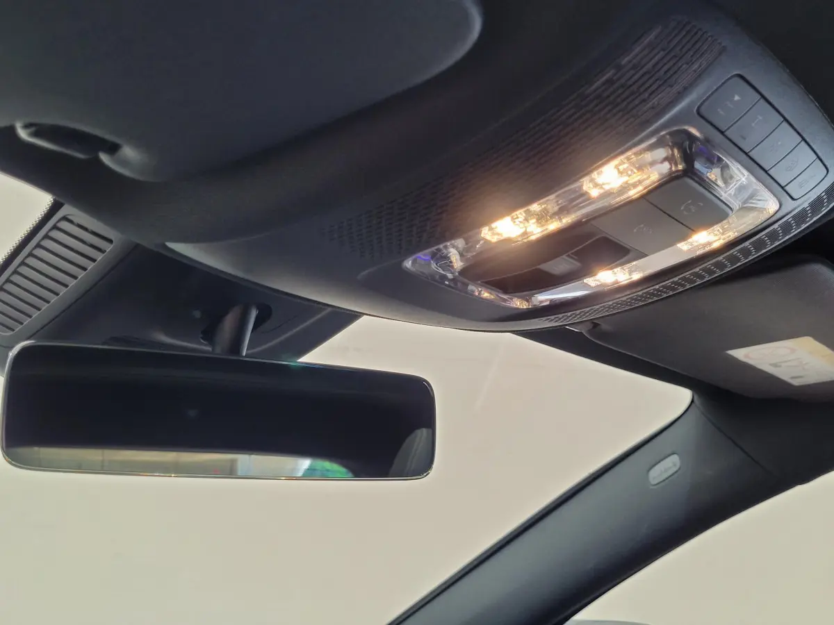 Plafonnier allumé et rétroviseur intérieur noir dans l'habitacle sombre d'un Mercedes GLA 200 D bleu 2022.