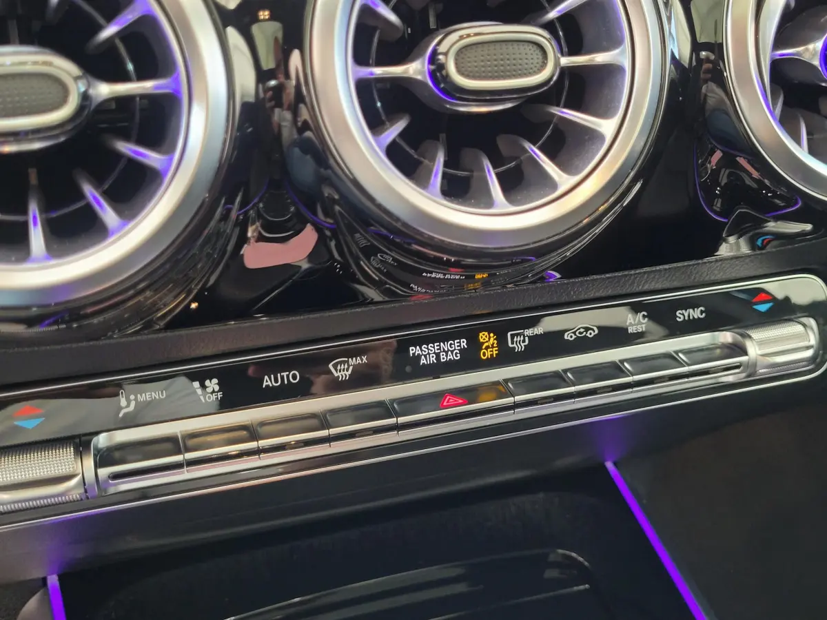 Gros plan sur les aérateurs ronds chromés et la console de climatisation digitale du Mercedes GLA 200 D bleu.