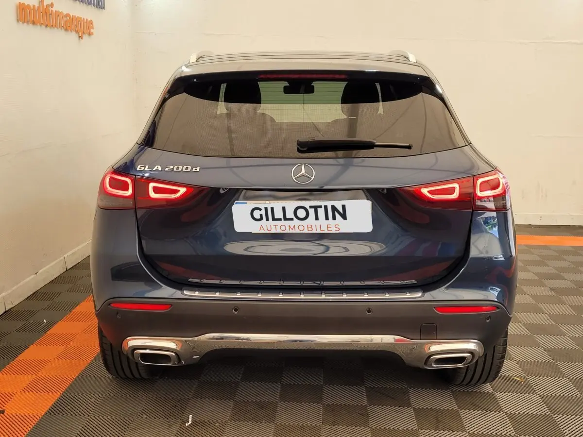 Vue arrière d'un Mercedes GLA 200d bleu 2022 avec feux LED allumés et double sortie d'échappement chromée.