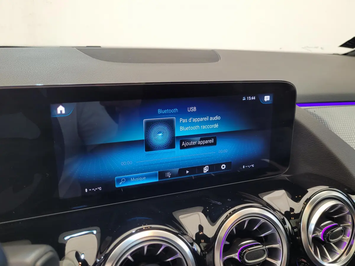 Écran tactile multimédia affichant Bluetooth et USB, avec aérateurs ronds et ambiance lumineuse violette sur tableau de bord noir.