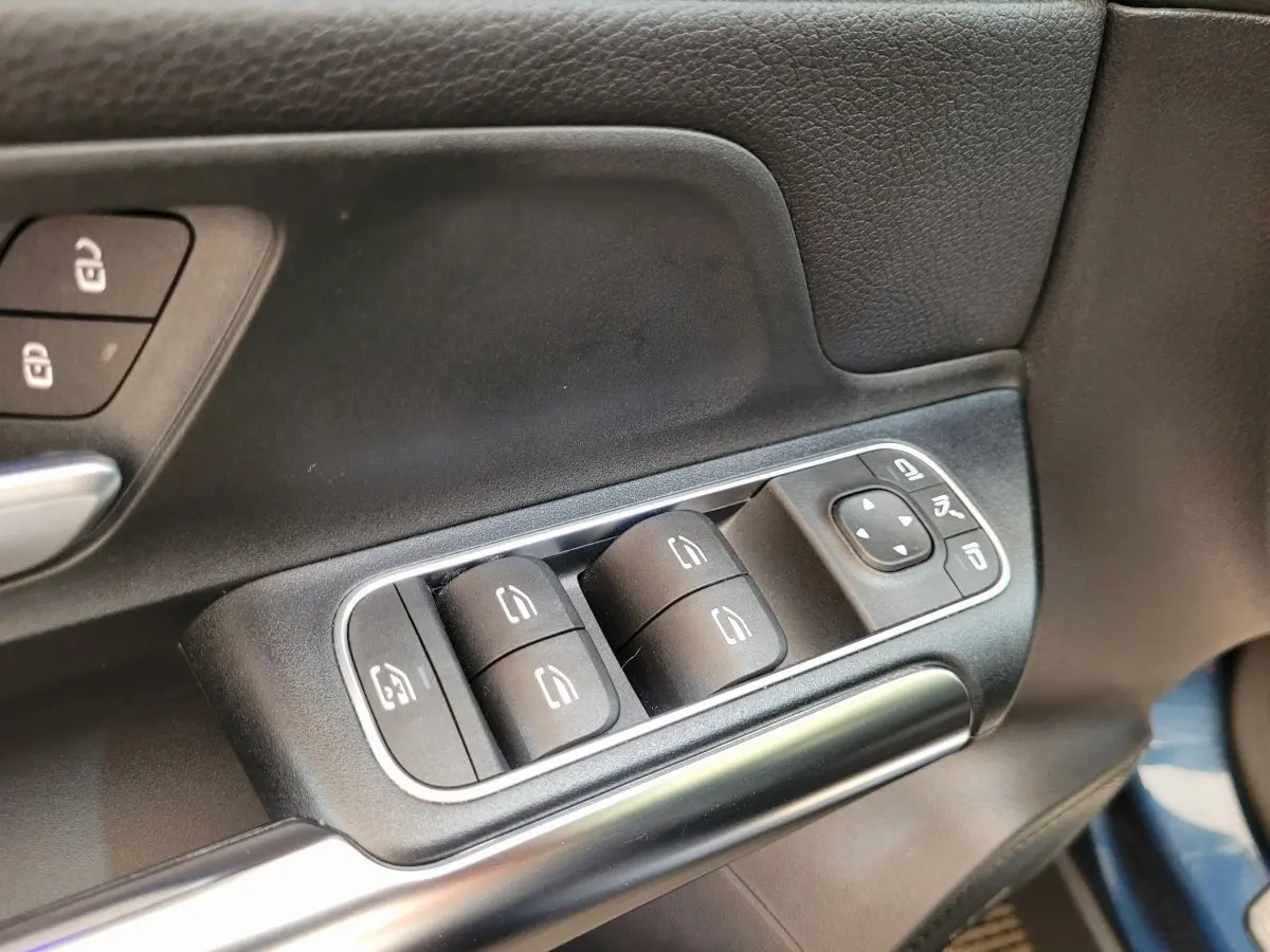 Gros plan sur les commandes de lève-vitres et rétroviseurs côté conducteur du Mercedes GLA 200 D Business Line bleu 2022.