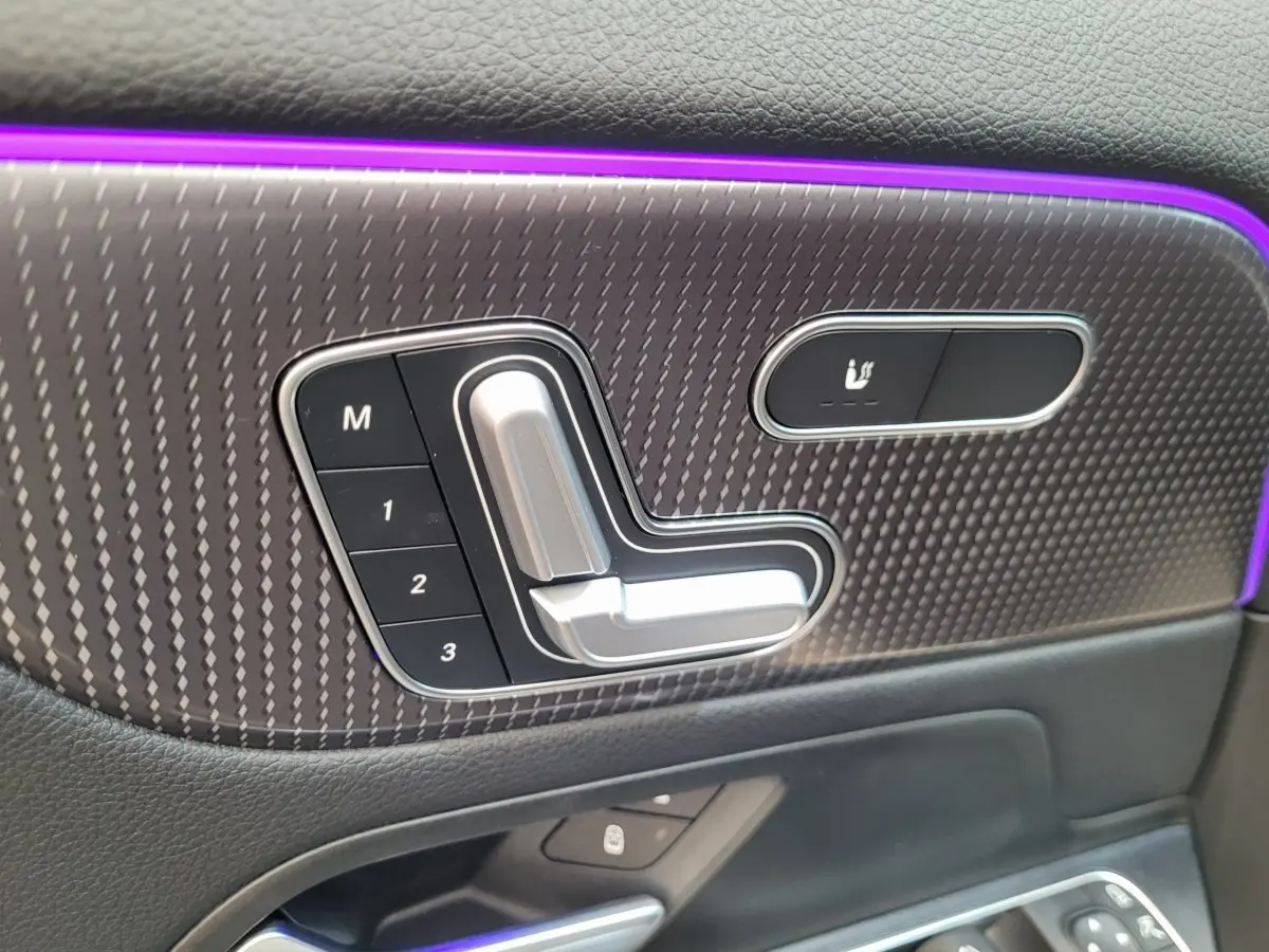 Détail des commandes de réglage électrique et mémoire des sièges sur la porte côté gauche d'un Mercedes GLA 200 D bleu 2022.