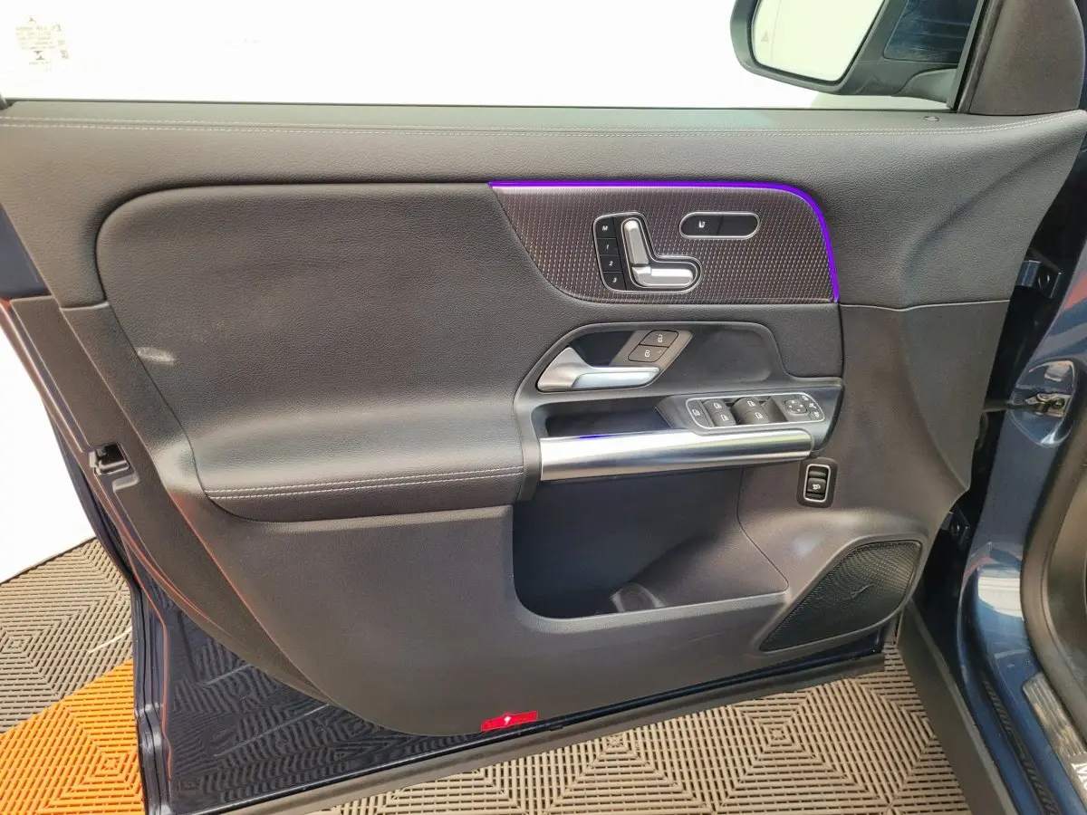 Porte côté gauche ouverte d'un Mercedes GLA 200 D Business Line bleu, avec commandes de siège et vitres intégrées.