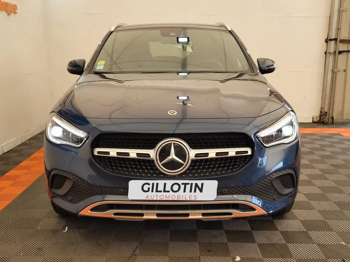 Vue frontale d'un Mercedes GLA 200 D Business Line bleu avec calandre chromée et phares LED allumés.