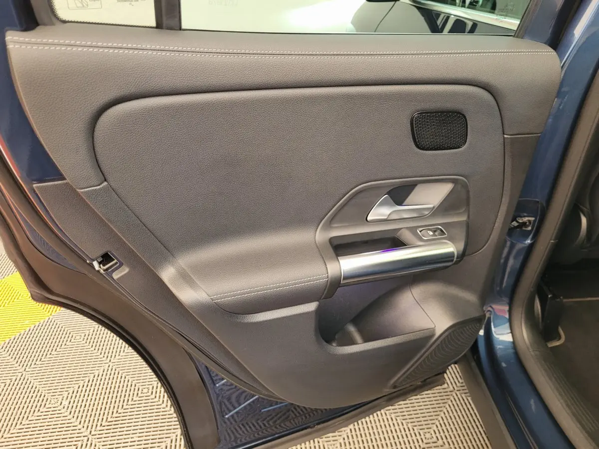 Gros plan sur la porte arrière gauche bleu foncé du Mercedes GLA 200 D avec garniture grise et poignée argentée.