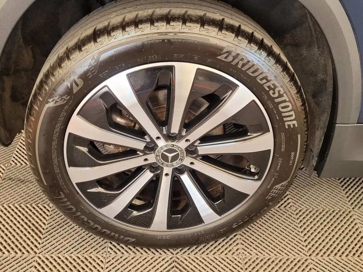 Gros plan sur la jante alliage noire et argentée avec logo Mercedes du pneu Bridgestone d’un GLA bleu 2022.