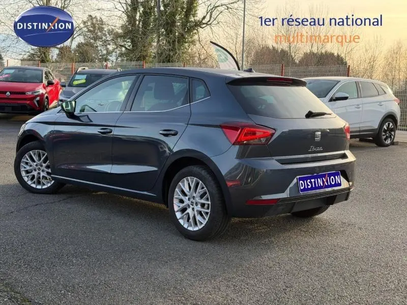 Vue 3/4 arrière droite d'une SEAT Ibiza 2025 gris magnétique métallisé avec jantes alliage et logo distinctif au garage.