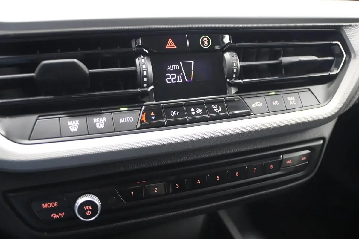 Gros plan sur la console centrale de la BMW Série 1 116d noire, affichant la climatisation automatique à 22°C.