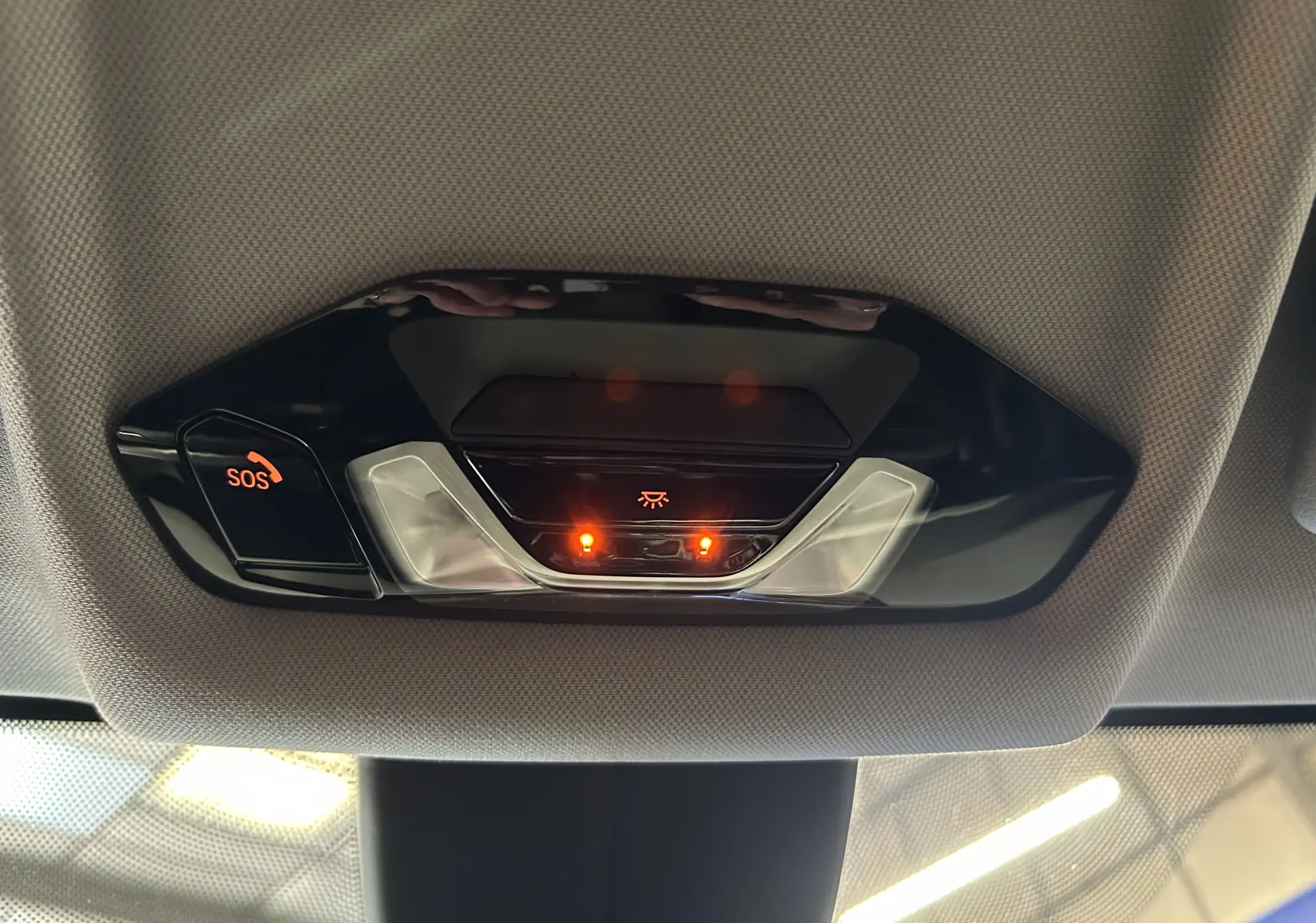 Plafonnier intérieur avec éclairage et bouton SOS allumé sur BMW Série 1 116d noir, vue de dessous vers l’avant.