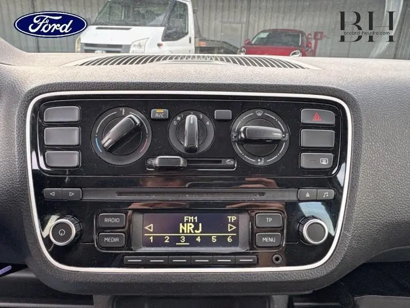 Tableau de bord central de Volkswagen Up blanc Candy 2014 avec commandes clim manuelle et radio NRJ affichée