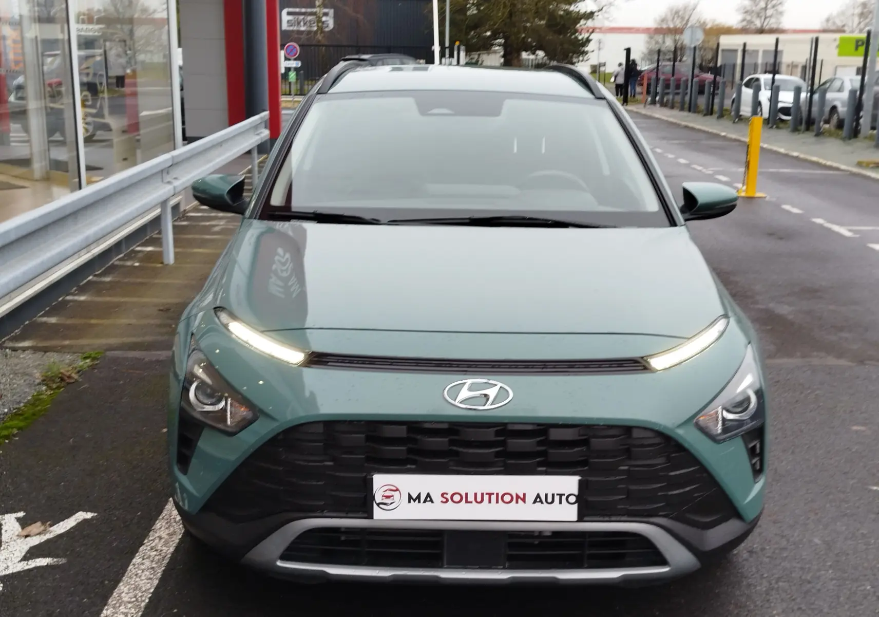 Vue frontale d'un Hyundai Bayon 2022 vert Elemental Brass Metal avec calandre noire et feux LED allumés.