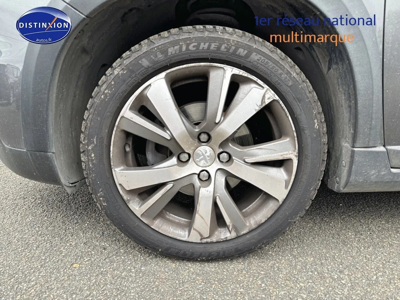 Gros plan sur la roue avant gauche d'un Peugeot 2008 gris platinium avec jante alliage et logo lion central.