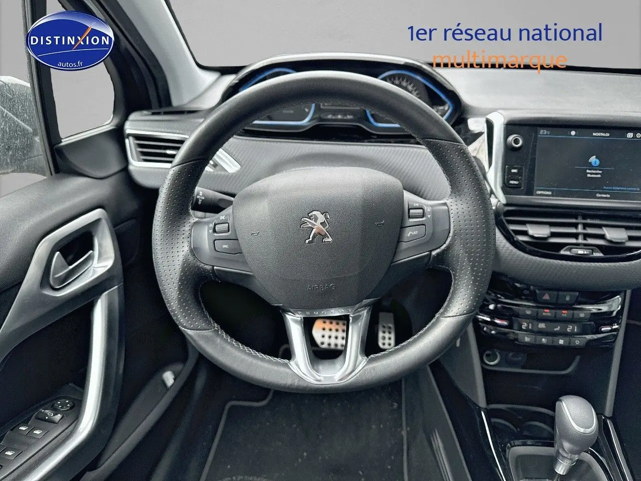 Vue rapprochée du volant en cuir noir et du tableau de bord moderne d'une Peugeot 2008 gris platinium de 2019.