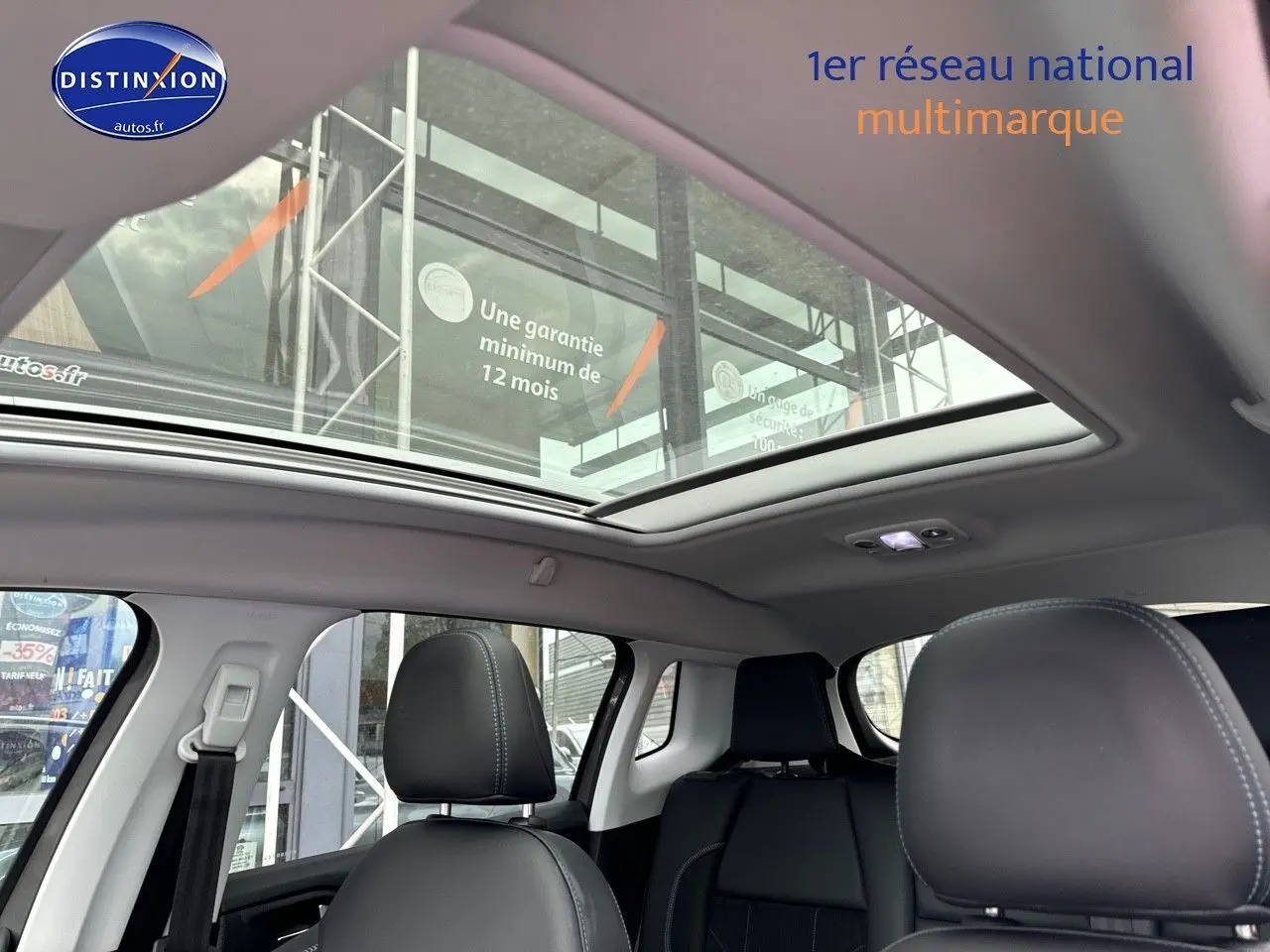 Intérieur du Peugeot 2008 gris platinium, vue sur les sièges avant et arrière avec toit panoramique ouvert.