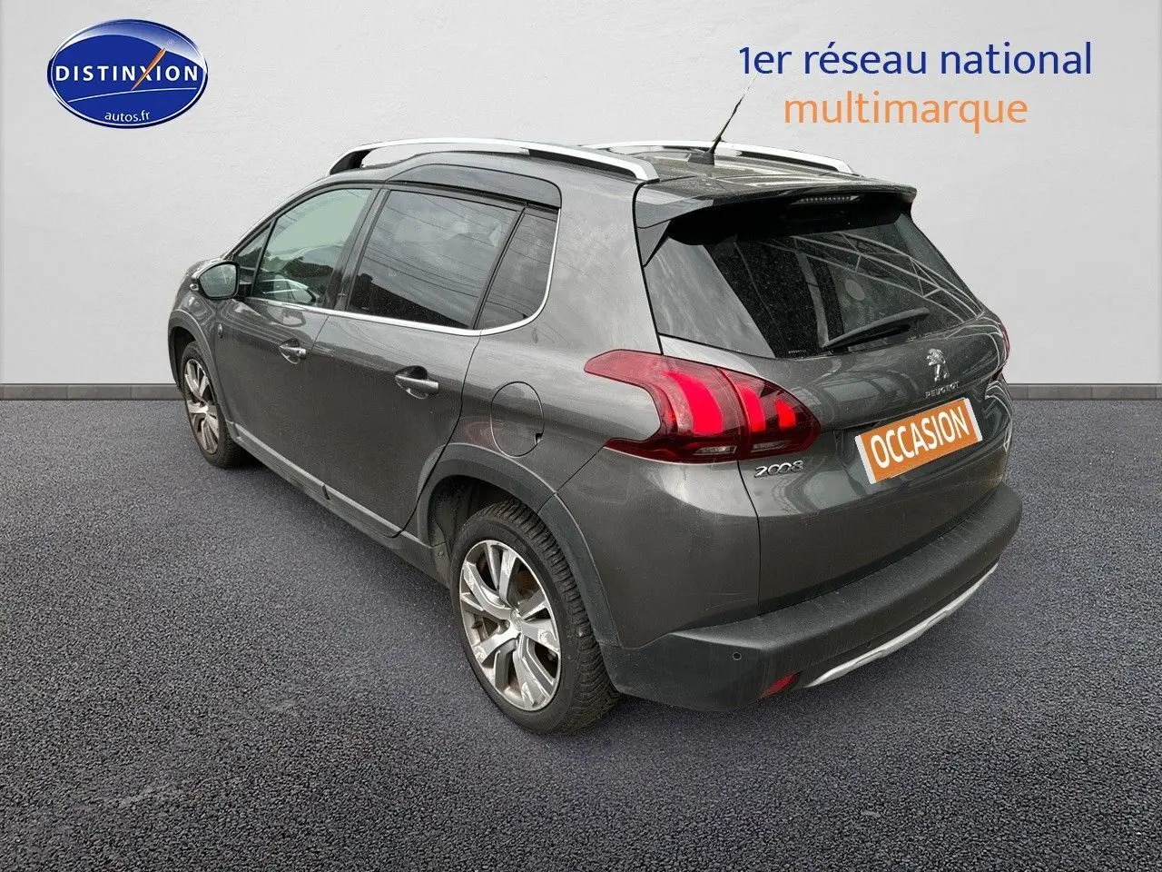 Vue 3/4 arrière gauche d'un Peugeot 2008 gris platinium avec barres de toit et jantes alliage 17 pouces.