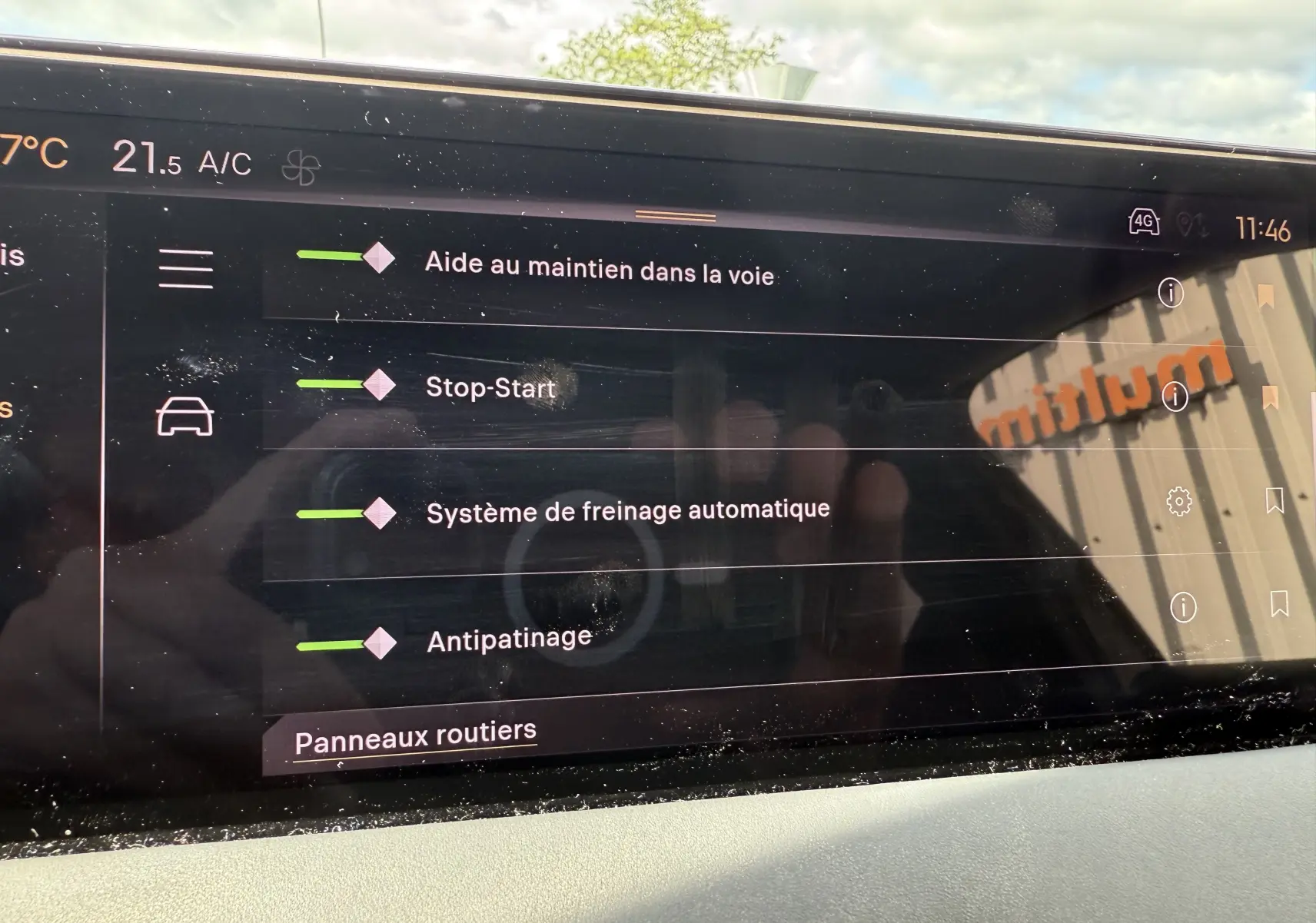 Écran tactile intérieur du DS3 2024 affichant les aides à la conduite et la climatisation, avec reflet extérieur.