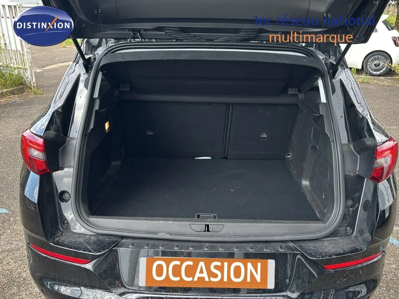 Coffre ouvert d’un Opel Grandland noir 2024, vue arrière montrant l’espace de chargement vide et les feux arrière rouges.