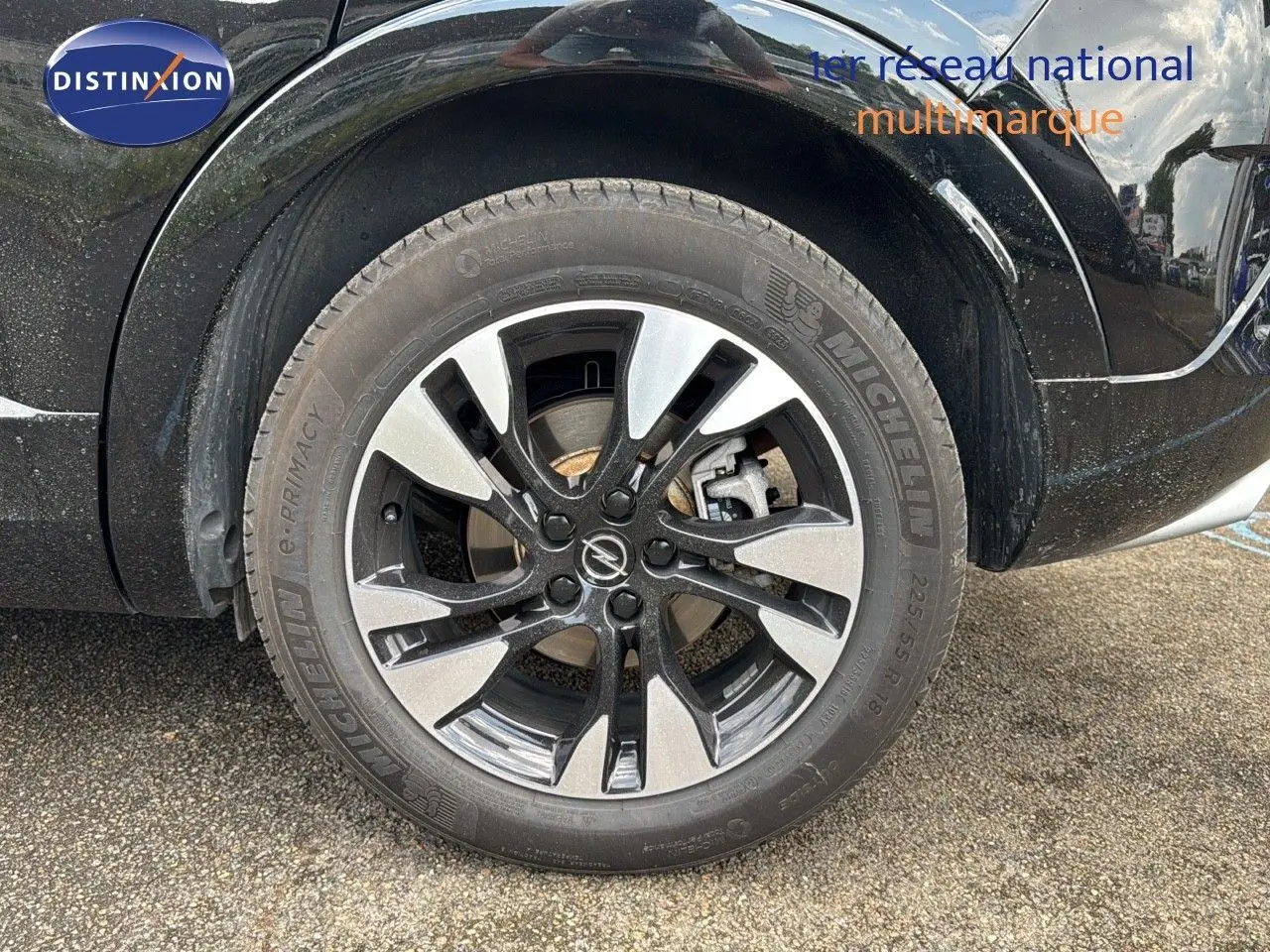 Gros plan sur la roue avant gauche noire de l'Opel Grandland 1.6 Turbo 225ch Hybride GS avec jante bi-ton distinctive.