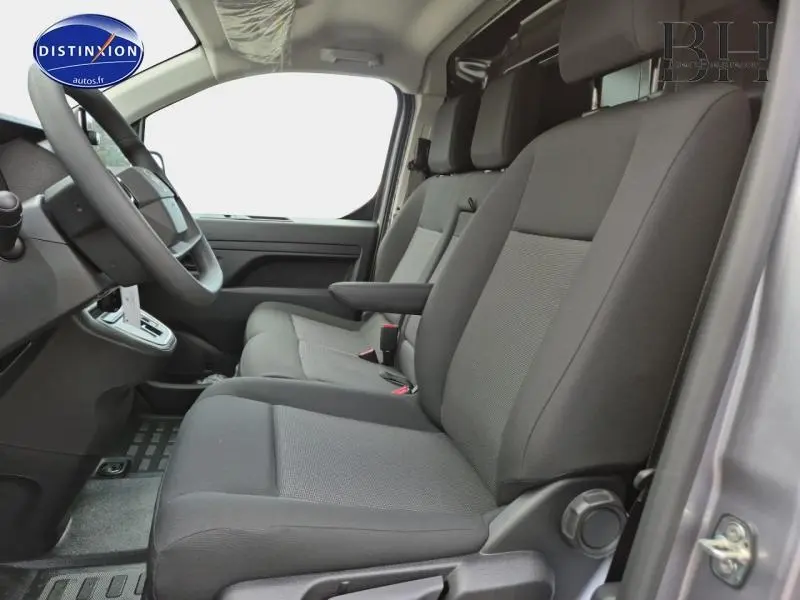 Vue intérieure côté conducteur du Citroën Jumpy Fourgon XL gris acier, sièges bi-ton noir et gris avec accoudoir central.