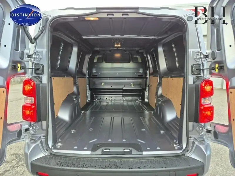 Vue arrière ouverte du Citroën Jumpy Fourgon XL gris acier métal, montrant l'espace de chargement vide avec habillage bois sur les parois.