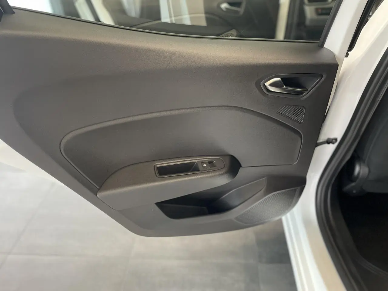 Vue rapprochée de la porte arrière droite noire de la Renault Clio 1.5 Blue dCi blanche avec poignée et commande de vitre.