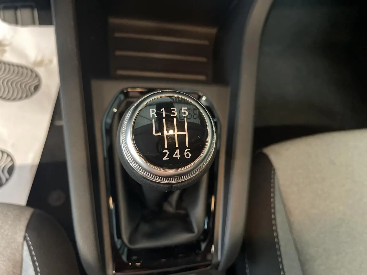 Gros plan sur le levier de vitesses manuel noir de la Renault Clio 2025 avec sellerie tissu gris visible.