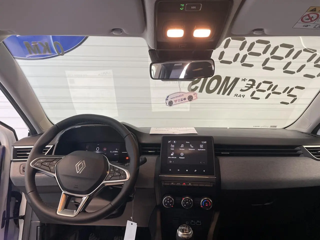 Vue intérieure frontale du tableau de bord de la Renault Clio 2025 avec volant multifonction et écran tactile central.