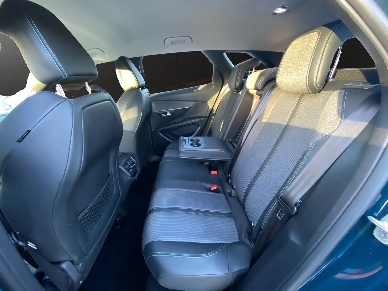 Vue intérieure arrière côté droit du Peugeot 3008 Bleu Celebes, sièges en cuir et tissu avec accoudoir central rabattable.