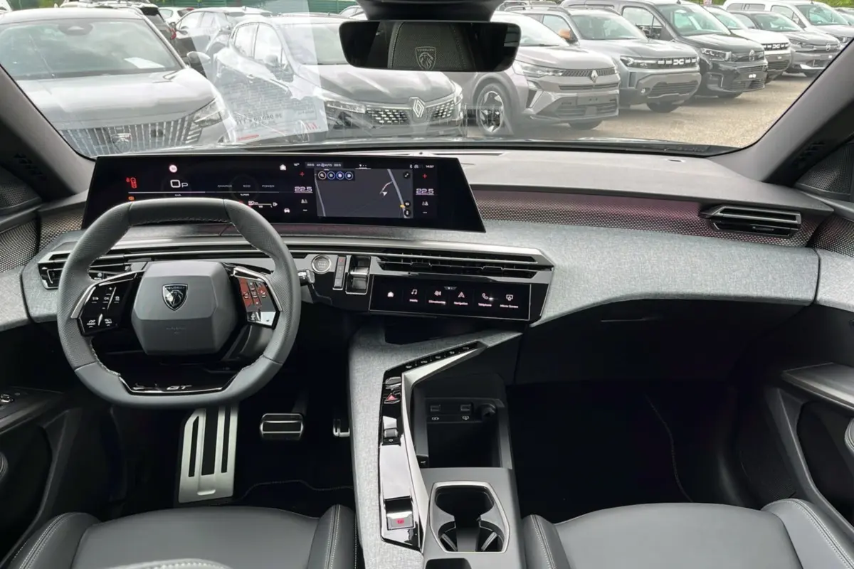 Vue intérieure frontale du Peugeot 5008 Hybrid 145 GT 2025, tableau de bord moderne avec écran large et volant cuir multifonctions.