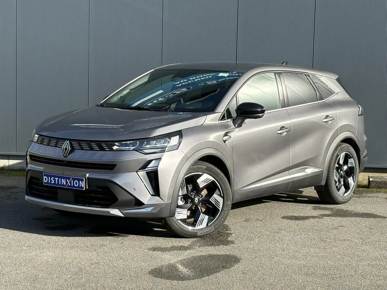 Renault Symbioz gris Cassiopée en 3/4 avant droit avec jantes 18 pouces et calandre moderne.