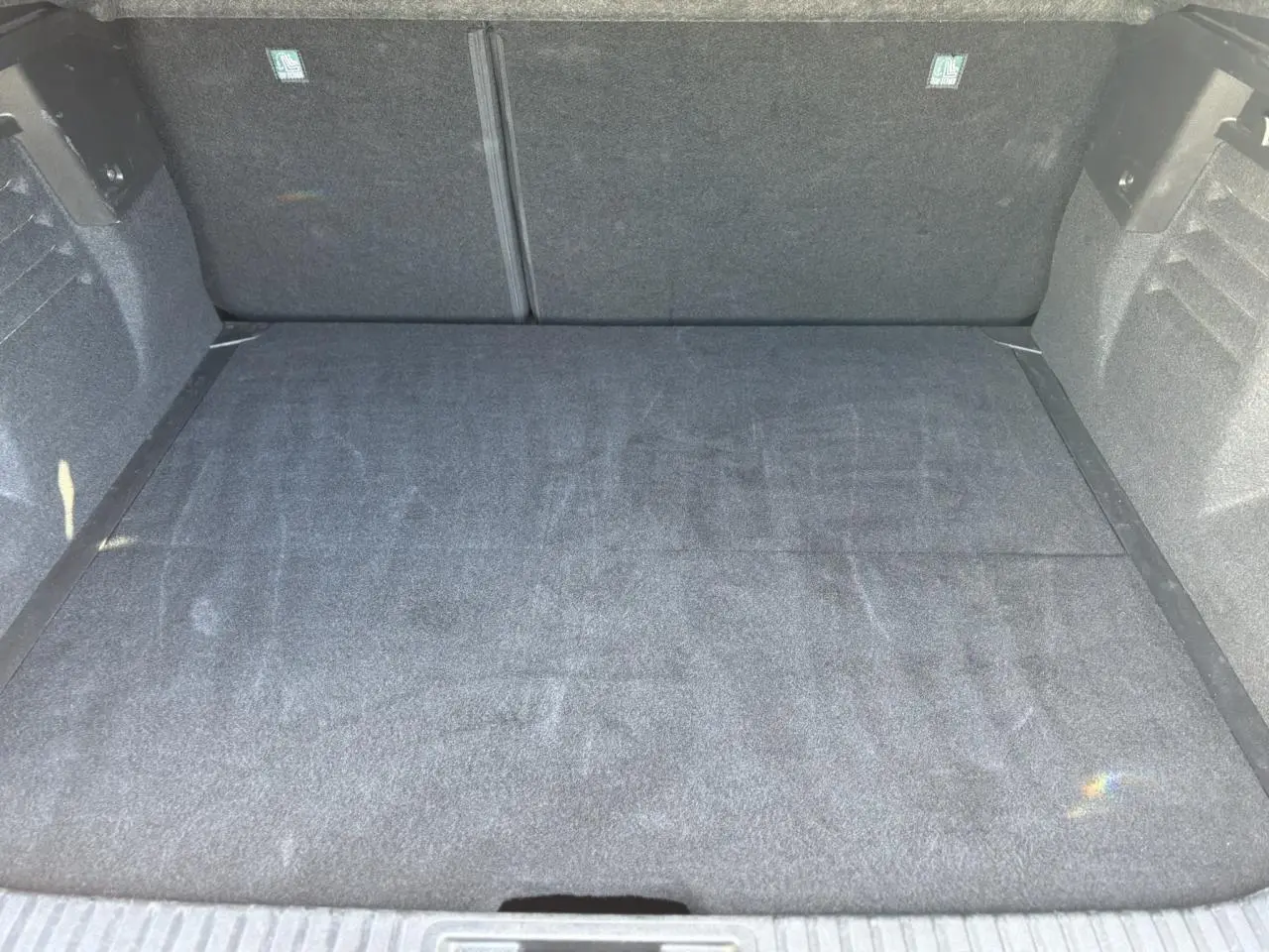 Vue plongeante sur le coffre spacieux et propre du Renault SYMBIOZ gris Cassiopée, sans chargement visible.