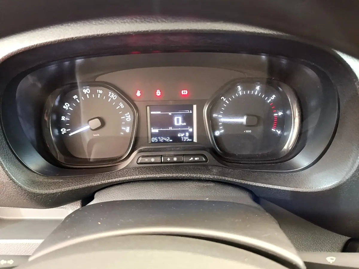 Gros plan sur le tableau de bord du Toyota Proace Verso gris clair, affichant le compteur et les voyants allumés.