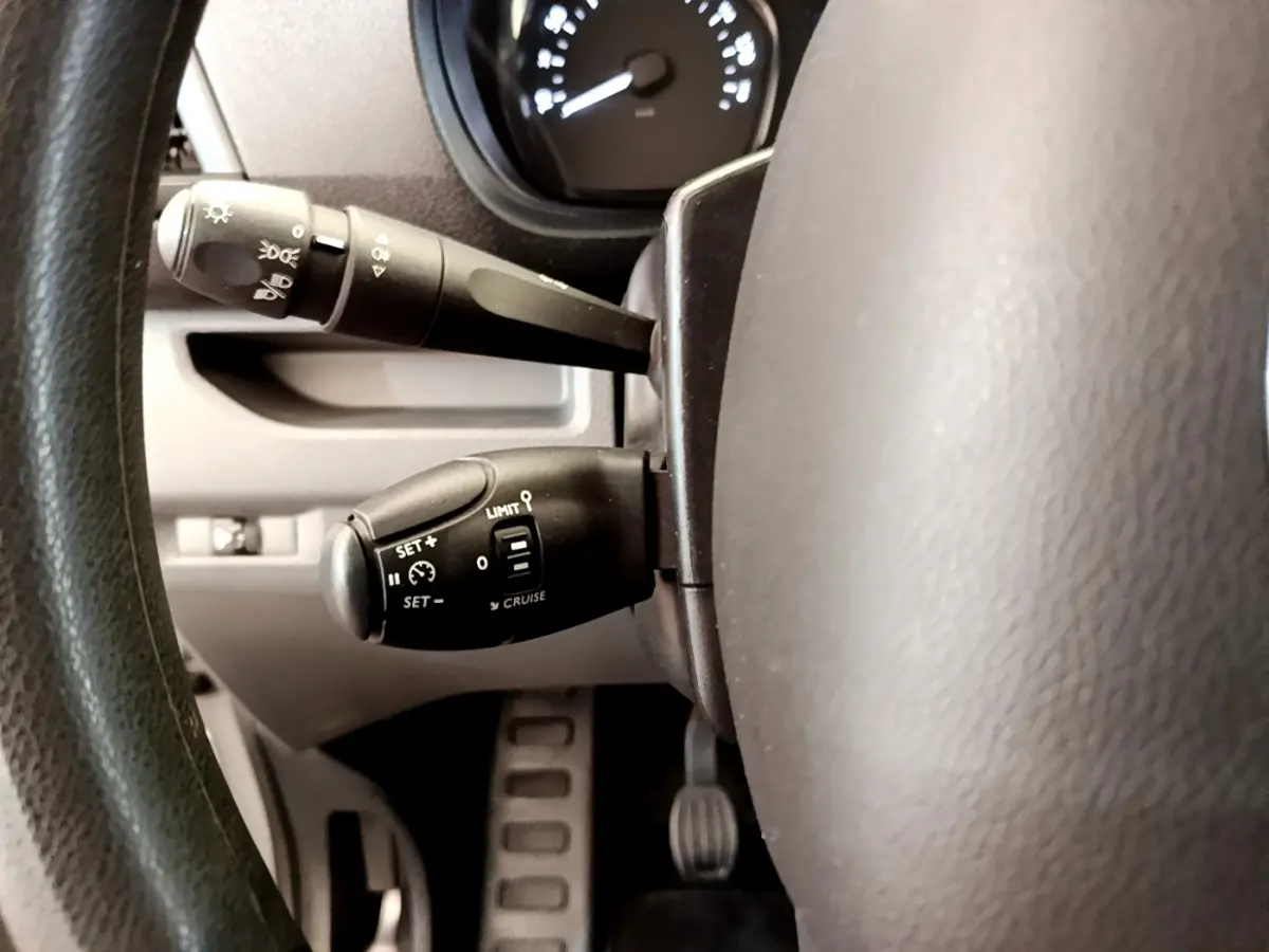 Gros plan sur la commande du régulateur de vitesse et des phares derrière le volant du Toyota Proace Verso gris clair 2019.