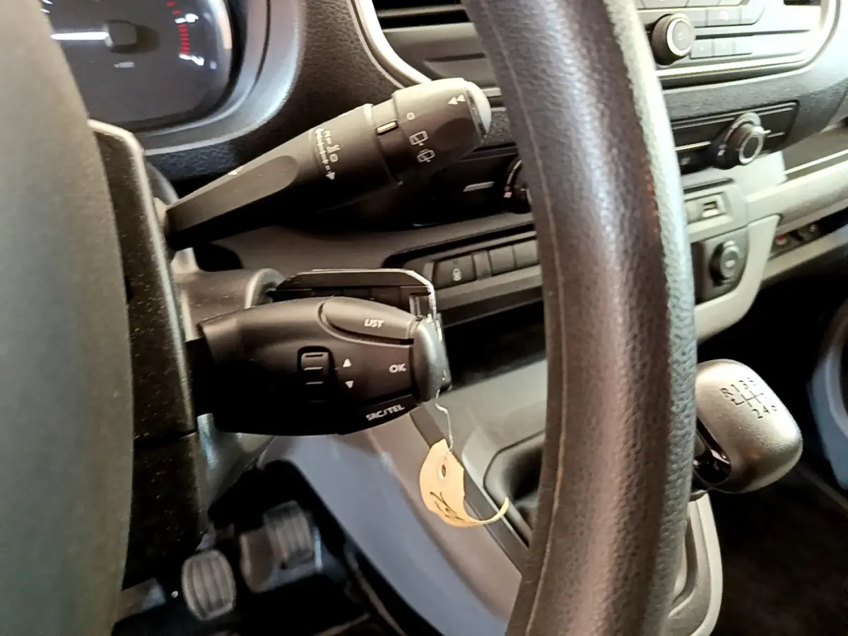 Vue rapprochée du volant noir et levier de vitesses manuel du Toyota Proace Verso gris clair, tableau de bord en arrière-plan.