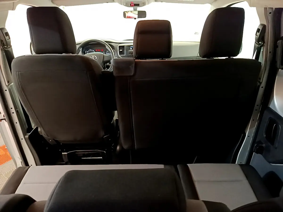 Vue intérieure arrière du Toyota Proace Verso 2019 montrant les sièges noirs et le tableau de bord gris clair.
