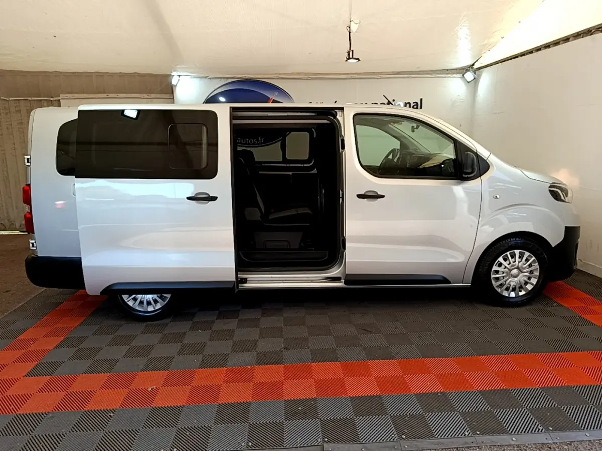 Profil droit d'un Toyota Proace Verso gris clair 2019 avec porte coulissante ouverte montrant l'intérieur sombre.