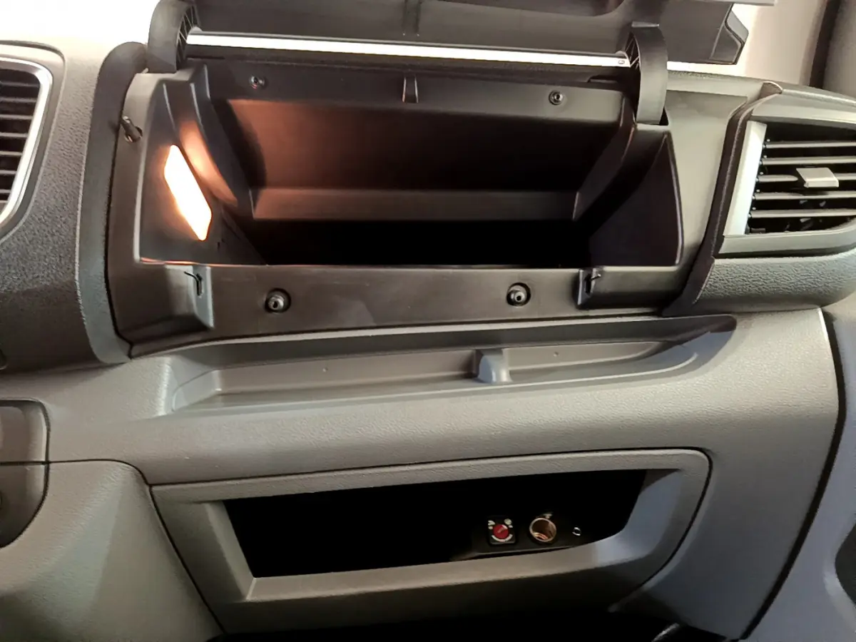 Intérieur du Toyota Proace Verso 2019 montrant la boîte à gants ouverte et le rangement inférieur gris clair côté passager.