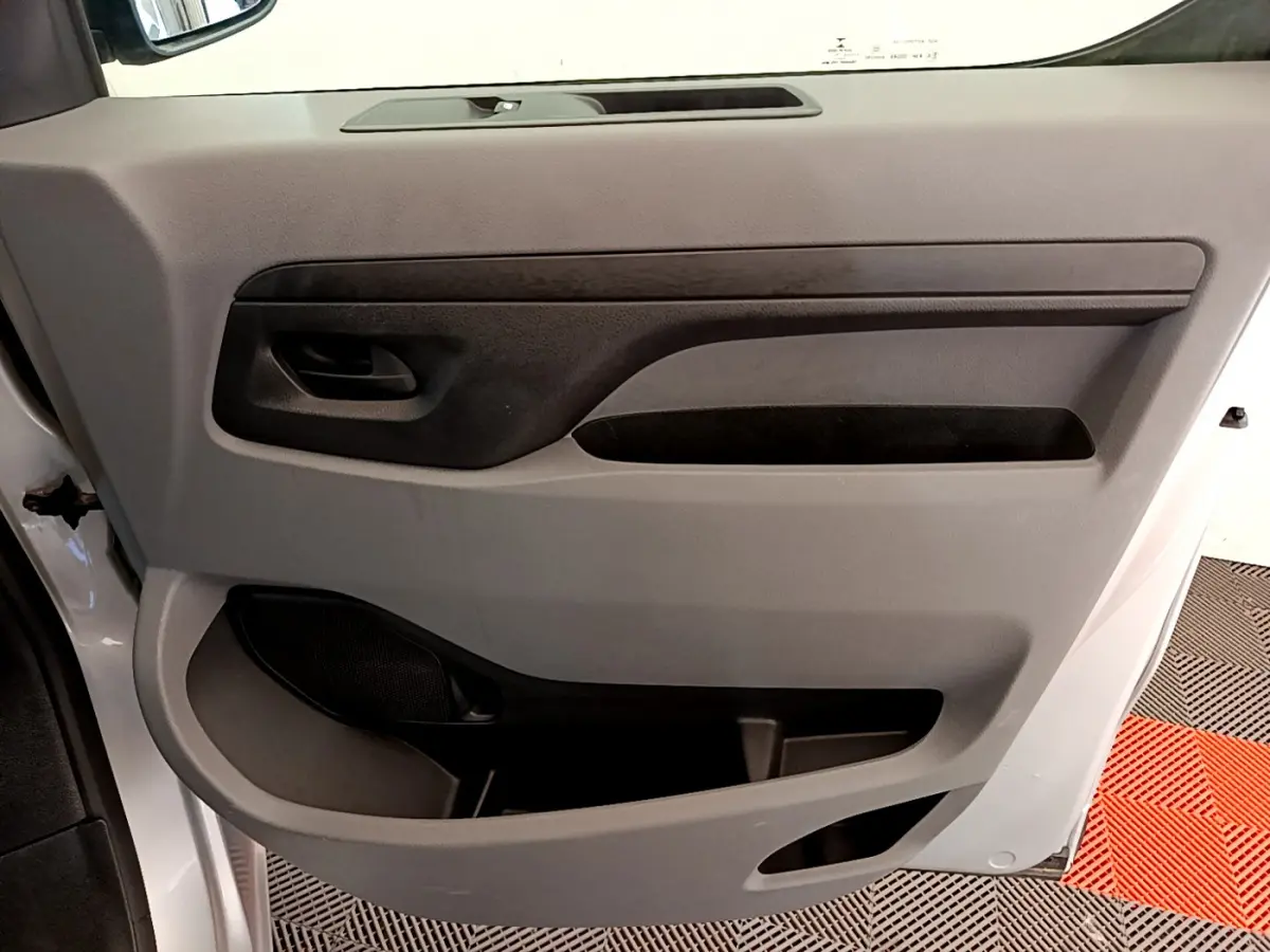 Gros plan sur la porte intérieure côté conducteur du Toyota Proace Verso gris clair, avec poignée noire et rangements intégrés.