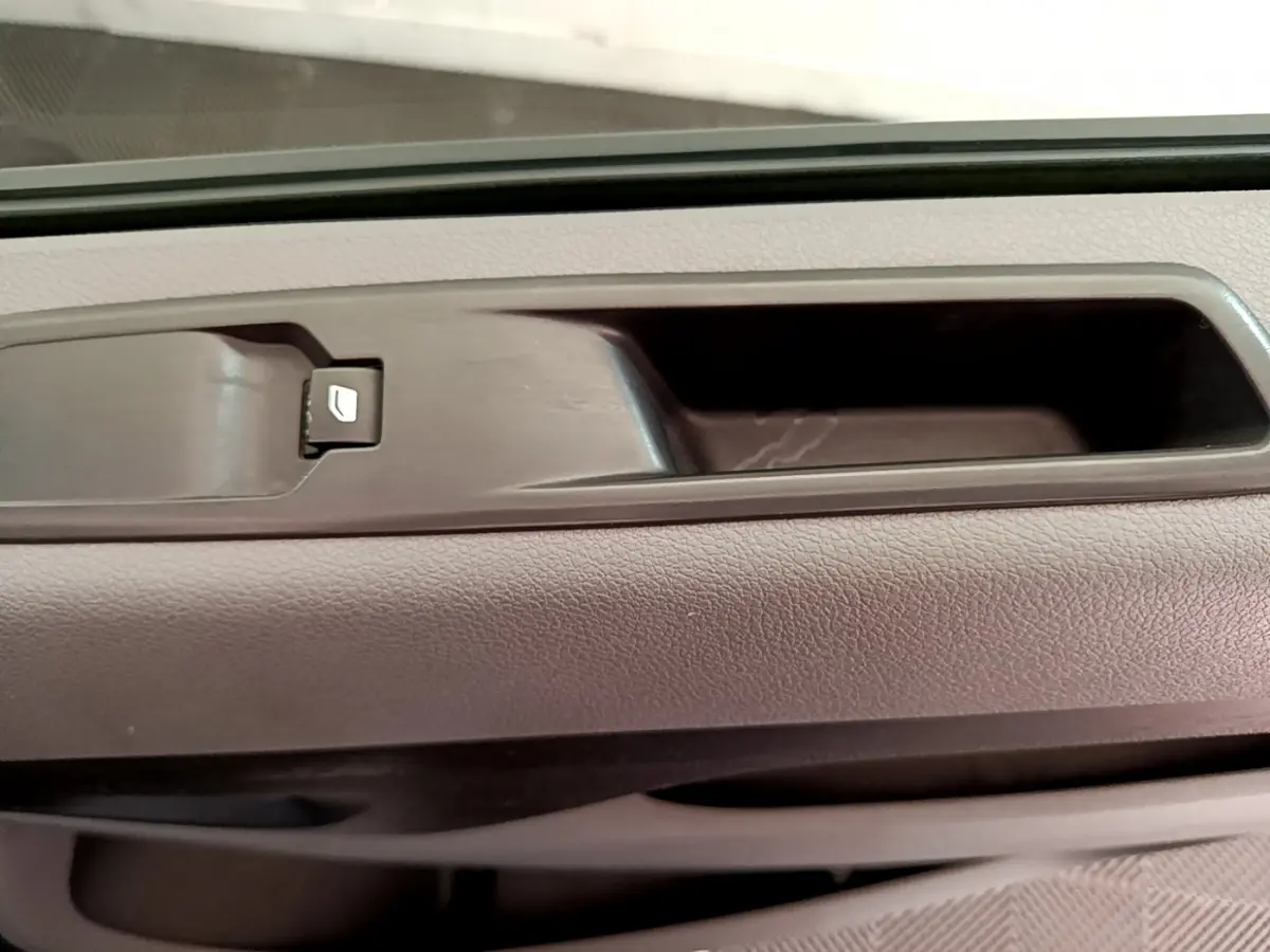 Gros plan sur la poignée intérieure et le bouton de verrouillage de porte du côté conducteur d’un Toyota Proace Verso gris clair.