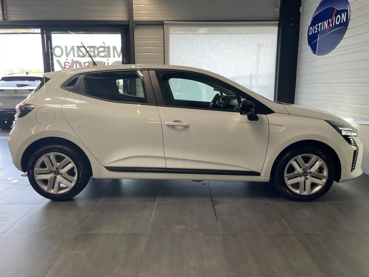 Profil côté gauche de la Renault Clio blanche 2025 avec jantes alliage et poignées couleur carrosserie.