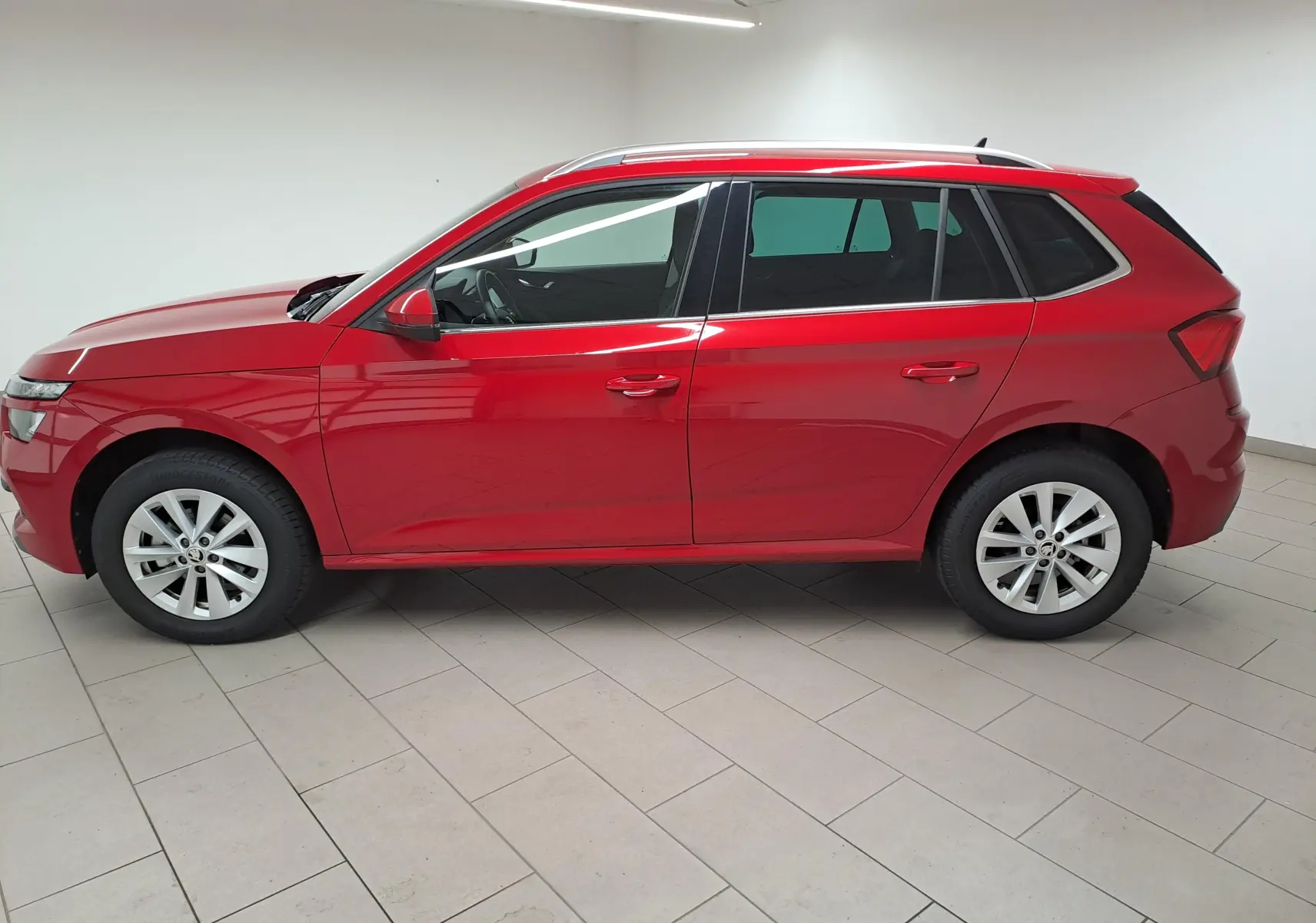 Profil côté gauche du Skoda Kamiq 2024 en Rouge Velvet métallisé, avec jantes alliage et toit ouvrant panoramique.