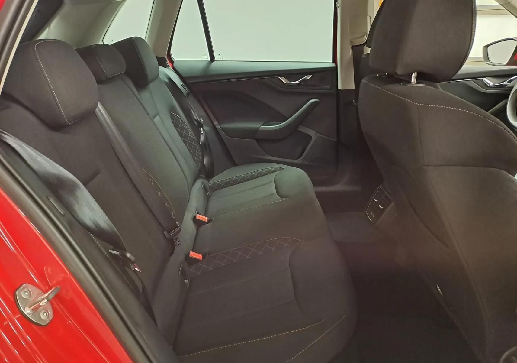 Vue intérieure côté gauche des sièges arrière noirs du Skoda Kamiq 2024 Rouge Velvet avec surpiqûres contrastantes.