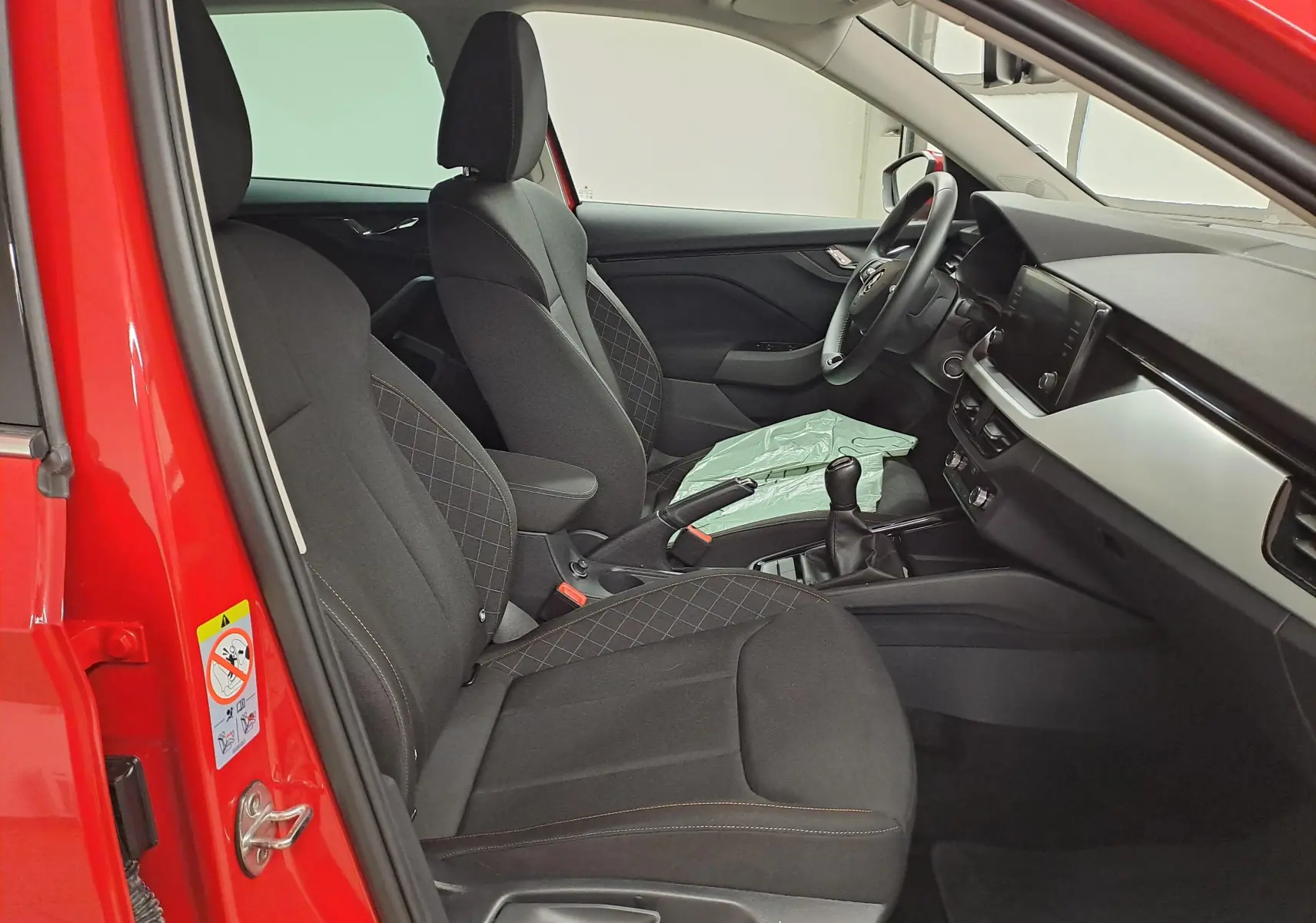 Intérieur côté conducteur du Skoda Kamiq Rouge Velvet 2024, montrant sièges noirs et tableau de bord moderne avec boîte manuelle.