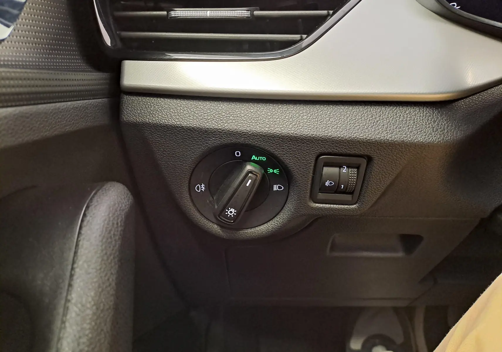Gros plan sur le bouton de commande des phares et réglage d’intensité lumineuse dans l’habitacle du Skoda Kamiq 2024.