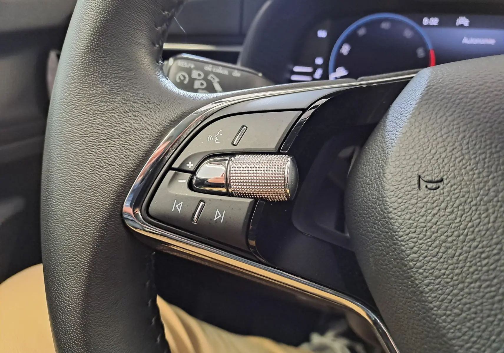 Gros plan sur les commandes du volant du Skoda Kamiq 2024, mettant en valeur la molette métallique et le cuir noir.