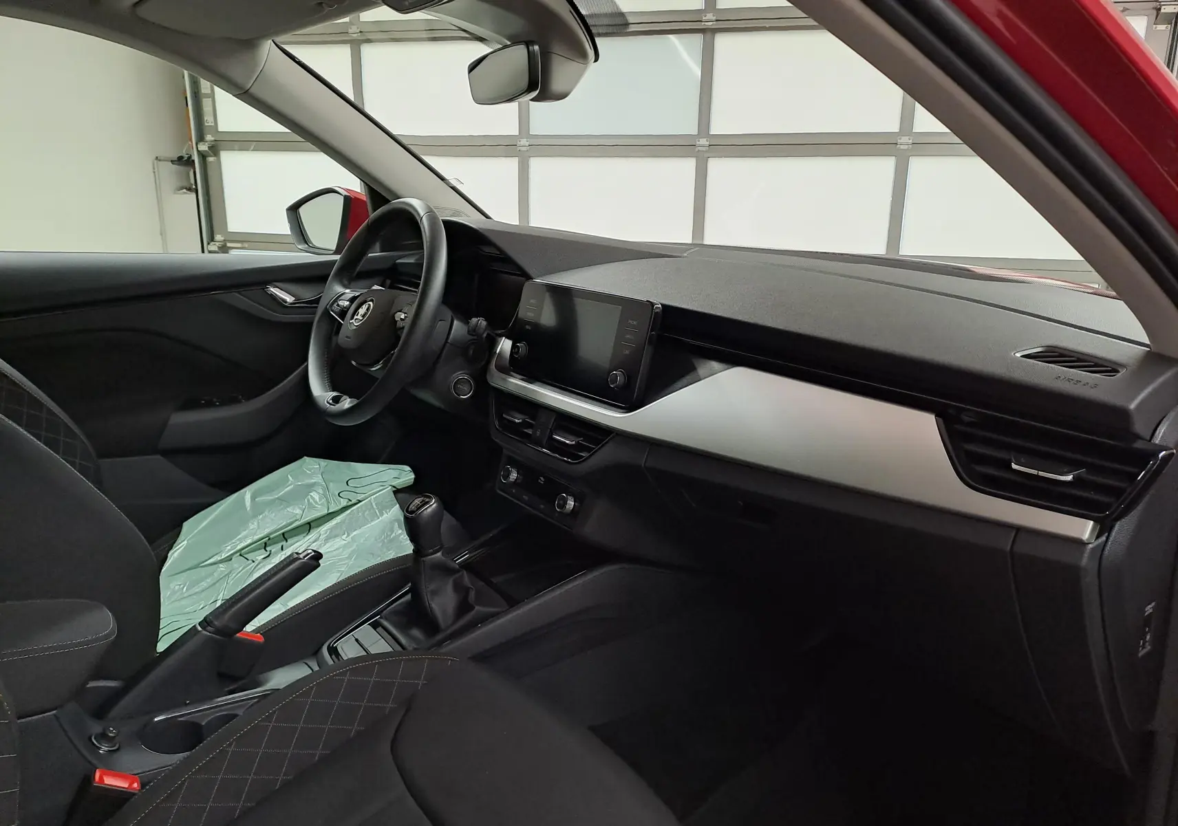 Intérieur du Skoda Kamiq 2024 vu côté conducteur, tableau de bord moderne avec écran tactile et volant multifonction.